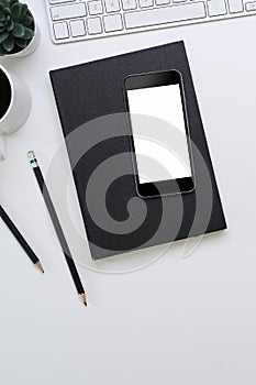 Smartphone with empty screen, notebook, plant and coffee cup and copy space on white background.