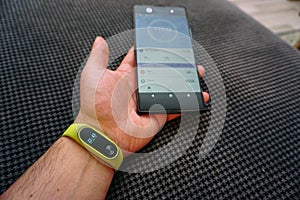 Smartphone and fitness activity tracker bracelet on the wrist close up view