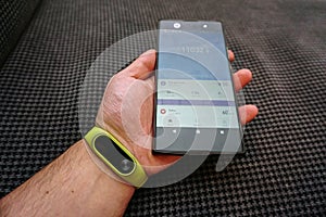 Smartphone and fitness activity tracker bracelet on the wrist close up view