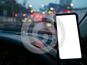 Smartphone or GPS device in a holder in car with blur background of traffic jams in the evening. Mockup white empty screen for
