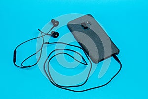 Smartphone in a gray textile case with connected headphones on a blue background