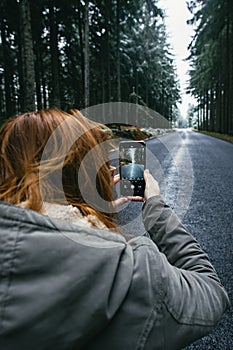 Smartphone in hand on the background winter road in the woods