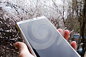 Smartphone in hand. Phone in hand. Phone on the street with light reflection.