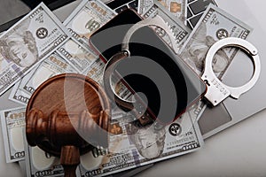 Smartphone with handcuff and judge gavel on cash. Cyber crime and law concept