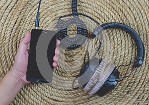 Smartphone headphone music on a jute rope background