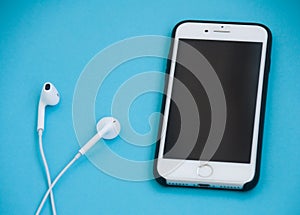 Smartphone and headphones on a blue background. Music concept