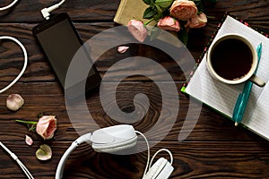 Smartphone, headphones, coffee cup on a wooden table. Top view flat lay background.