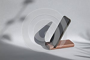 Smartphone on a holder, mockup with shadow on wall background