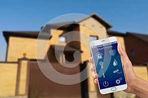 Smartphone with home security app in a hand on the building background