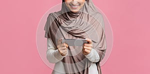 Smartphone in horizontal orientation in hands of unrecognizable woman in hijab