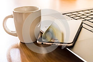 Smartphone and laptop with a coffee cup, working remotely during coronavirus, smartwork with pc and cell phone concept photo