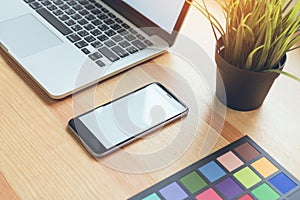 Smartphone and laptop on table in office room, for graphics display montage.