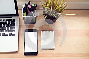 Smartphone and laptop on table in office room, for graphics display montage.