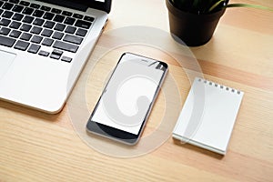 Smartphone and laptop on table in office room, for graphics display montage.