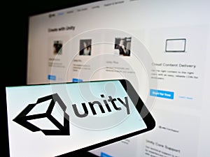 Smartphone with logo of US video game engine developer Unity Software Inc. on screen in front of business website.