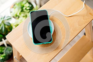Smartphone in mint silicone case is charged from a wireless charger