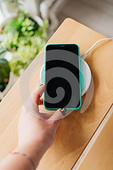 Smartphone in mint silicone case is charged from a wireless charger