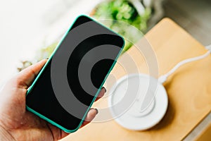 Smartphone in mint silicone case is charged from a wireless charger