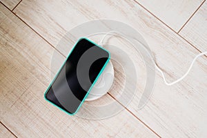 Smartphone in mint silicone case is charged from a wireless charger