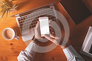 Smartphone mock up overhead shot, businessman holding mobile phone with blank screen over office desk