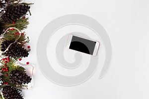 Smartphone mockup for christmas. fir branches, cones and christmas decorations on white background. flat lay top view.