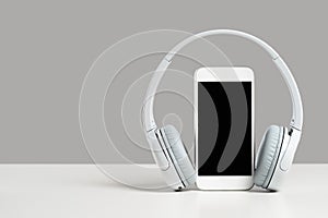 Smartphone mockup display with grey wireless headphones on gray background photo