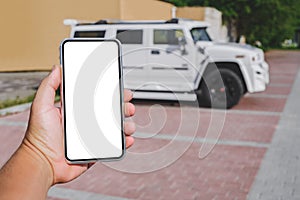 Smartphone mockup in the hand of a man. Against the background of a white SUV. Online purchase, car rental. The concept of road