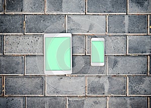 Smartphone and mockup tablet pc against a brick wall