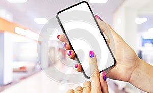 Smartphone mockup in woman hand with business centre background. Modern frameless smartphone mock up with blank white screen. Empt