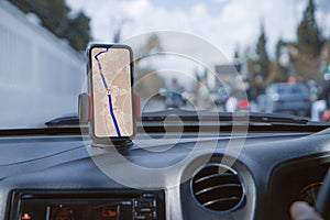 Smartphone with navigation route on screen mounted on phone holder at car dashboard. mobile phone with map gps navigation in car