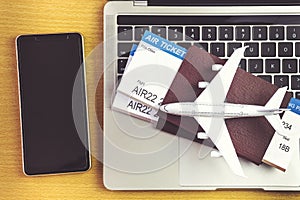 Smartphone near laptop computer and airplane on table. Online ticket booking concept