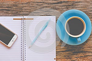 Smartphone with notebook and cup of strong blue coffee cup