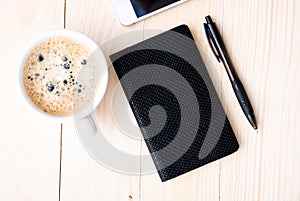 Smartphone with notebook and cup of strong coffee