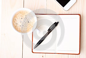 Smartphone with notebook and cup of strong coffee