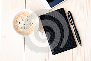 Smartphone with notebook and cup of strong coffee