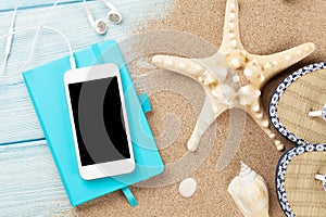 Smartphone and notepad on wood with starfish and shells