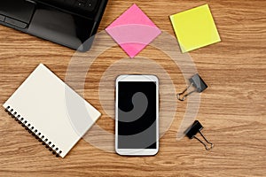 Smartphone and office supplies on wooden table, top view