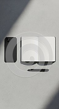 Smartphone, open notebook, and pen arranged on a textured light gray surface. The