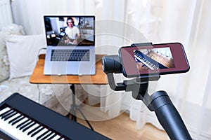 A smartphone placed on a gimbal used as second camera for online piano lessons. photo