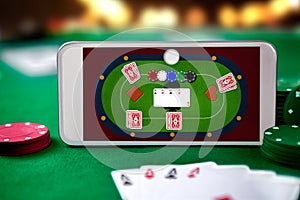Smartphone with poket table on screen, playing cards and chip cards on poker table photo
