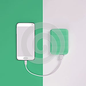 Smartphone and Powerbank on an green background. Power bank charges the phone