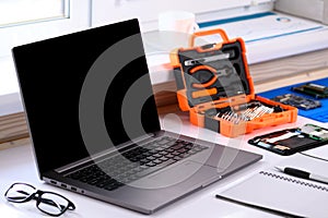 . Smartphone repair courses. There is a computer and a disassembled tablet on the table. Online learning