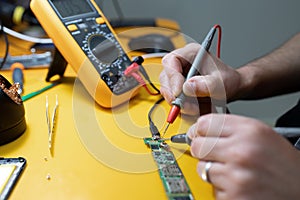 Smartphone repair in a service center. Hands of a professional master repairman repairing disassembled into pieces cell phone.