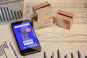 Smartphone runs an online shopping app with cardboard boxes. concept about this type of financial charts include stacks of bar
