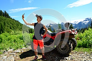Smartphone Selfie by Generation Y Teenager with ATV (All-Terrain Vehicle) Parked in Mountainous Forest Nature