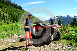 Smartphone Selfie by Generation Y Teenager with ATV (All Terrain Vehicle) Parked in Mountainous Forest Valley