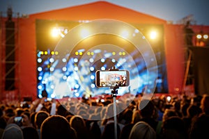 Smartphone on selfie monopod stick. Concert background