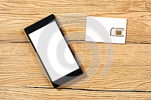 Smartphone and SIM card on office table, top view