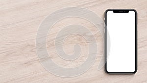 Smartphone similar to iPhone X mockup flat lay top view lying on wooden office desk banner with copy space