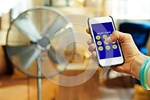 Smartphone with smart home app in female hand controlling fan